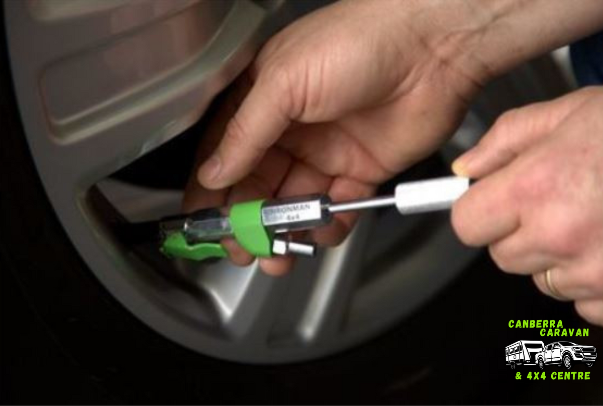 Person using a tool to check tire pressure on a car tire, with Canberra Caravan & 4X4 Centre logo.