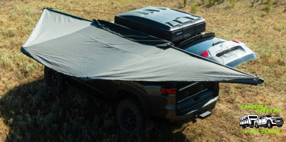 Car with a roof rack and tarp on a grassy field, featuring a brand logo in the corner.