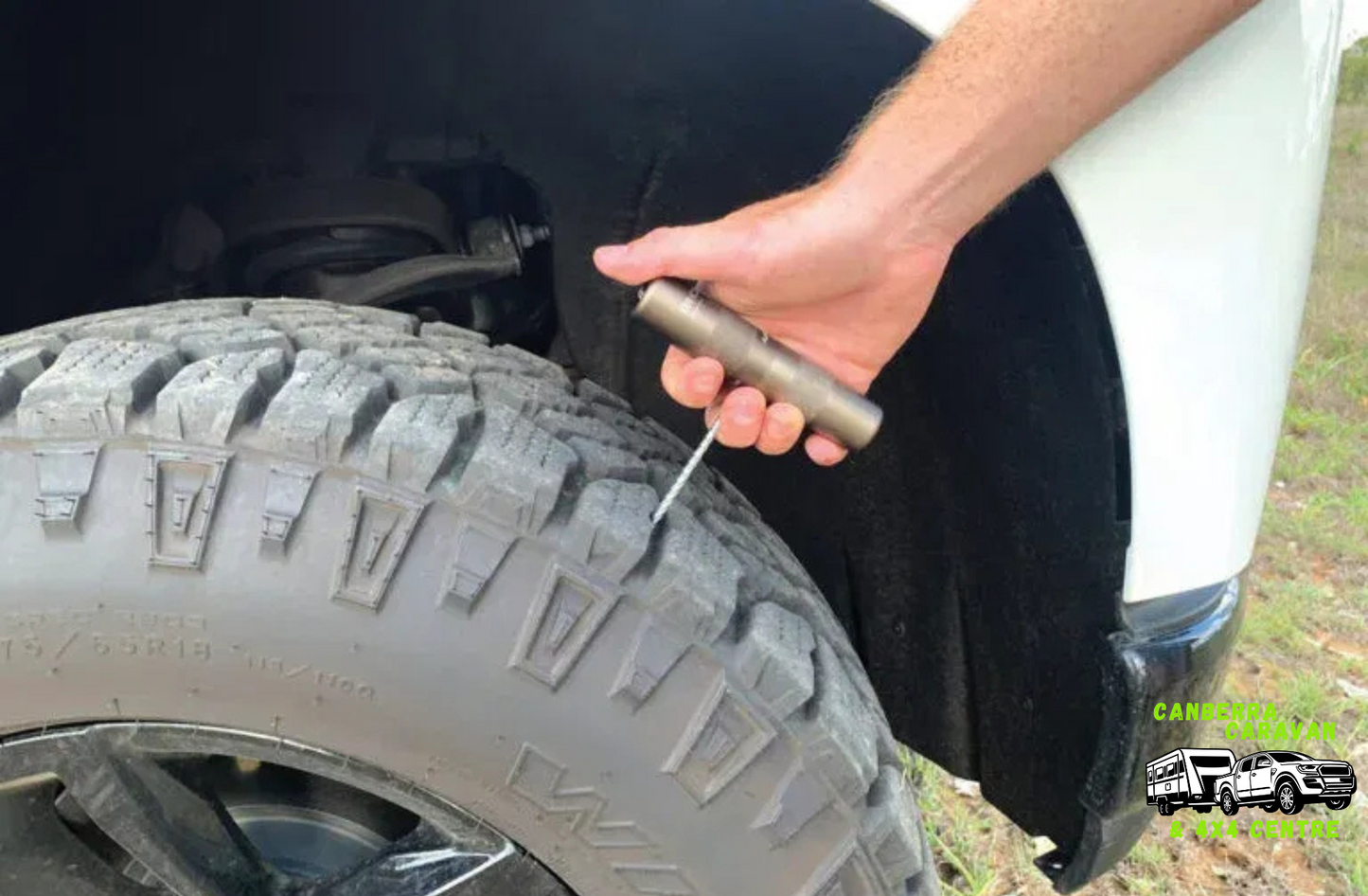 Person changing a tire with a tool next to a vehicle
